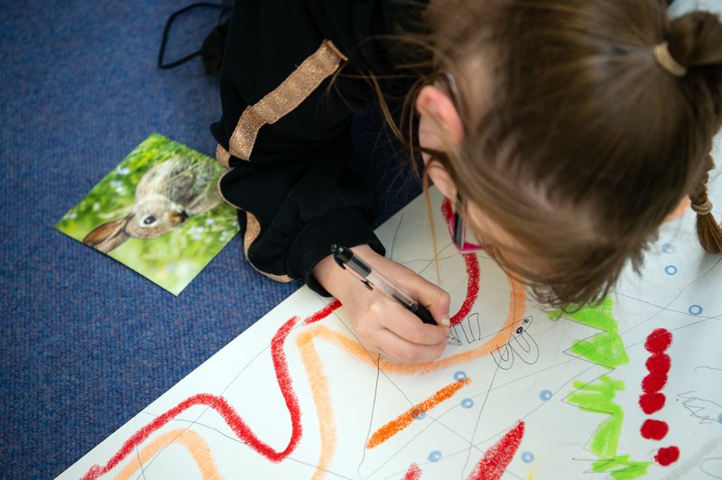 A child photographed from overhead looking down onto the picture they are drawing.