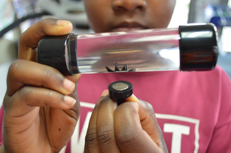 A plastic tube with a child holding a magnet underneath