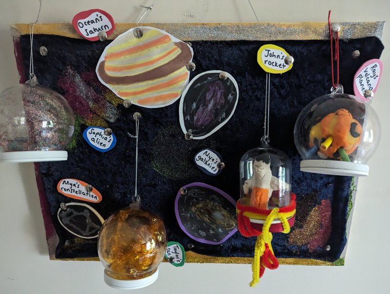 A space themed pin board with handmade objects made by children including rockets, planets and aliens.