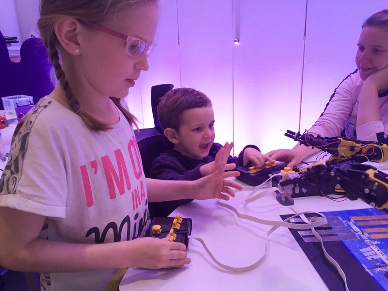 Two children and an adult in a room with low lighting playing with science equipment.