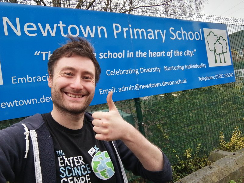 An adult with their thumbs up, in front of Newtown Primary School