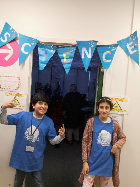 Two young people stood in a doorway under a banner saying science.